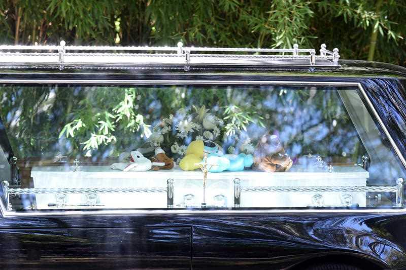 A hearse carrying coffins departs following the funeral for the Manrique family at the at the Holy Name Parish in Sydney