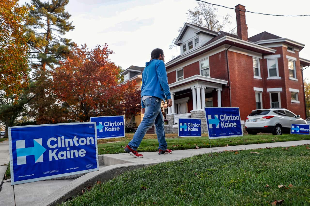 Blake Gibson walks past yard signs before entering a home serving as a canvassing site to train and organize supporters of Hillary Clinton in Cincinnati.