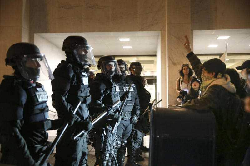 Police stand in front of people who march through downtown Portland, Oregon, to protest of the election of president-elect, Donald Trump.