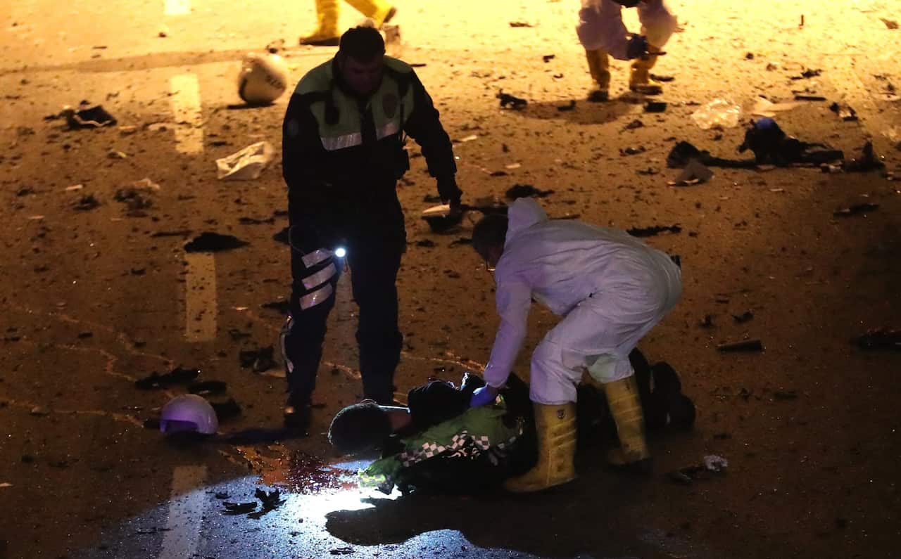 Crime scene investigators inspect a police officer's body at the scene after an explosion around Vodafone Arena Stadium in Istanbul, Turkey.