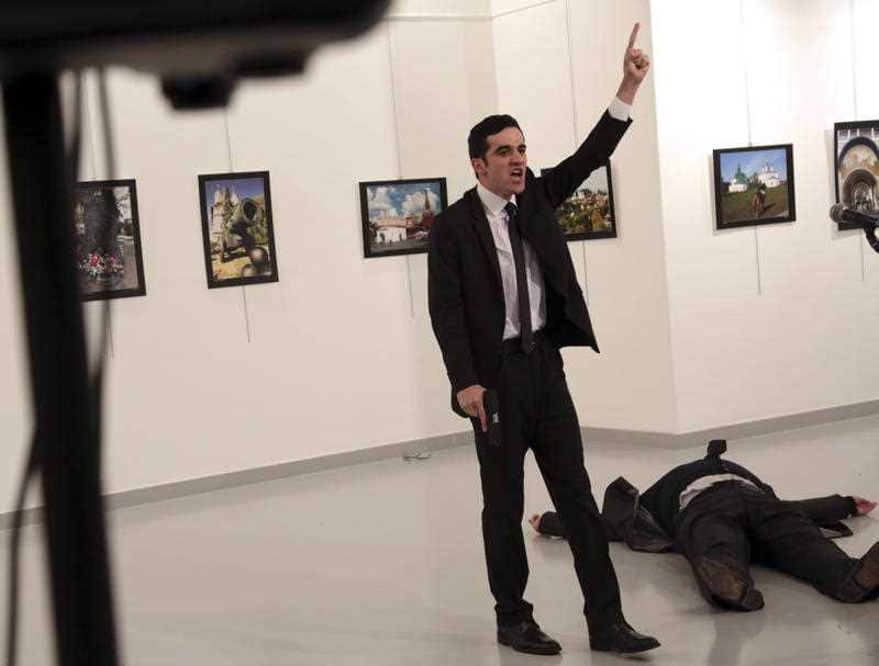 Gunman (C) stands near slain Russia's ambassador to Turkey, Andrey Karlov's body (down) after he shot him during an art exhibition in Ankara, Turkey