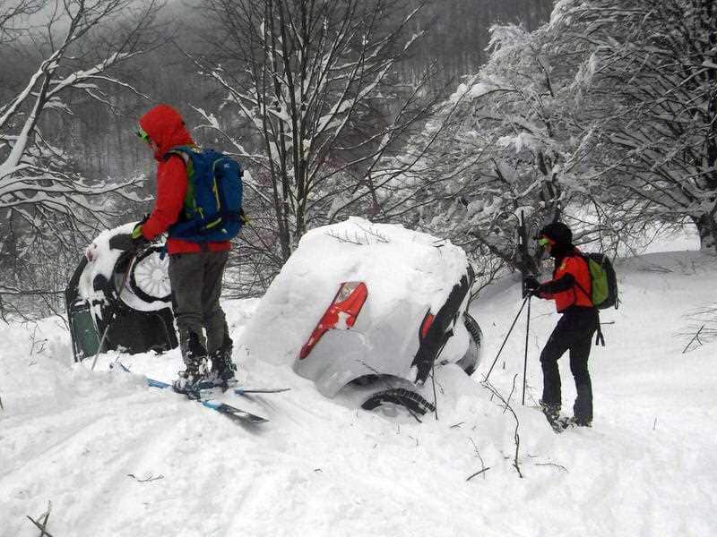 Rescuers stand by two cars submerged in snow as they work in front of the Rigopiano Hotel, following an avalanche in Farindola, Italy
