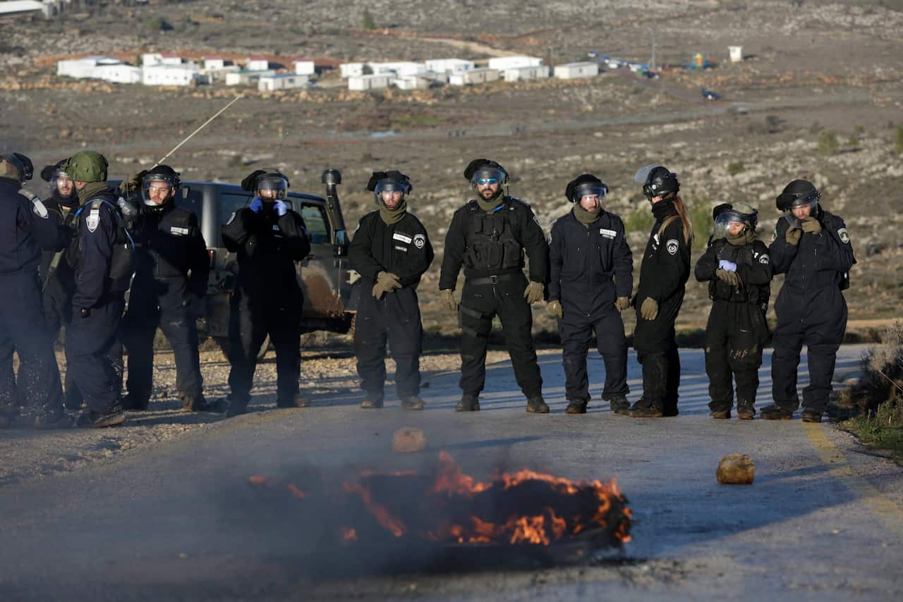 Police stand by as Israeli settlers burn tires and block an entrance ahead of the upcoming eviction of the illegal Jewish settlement of Amona, in the West Bank