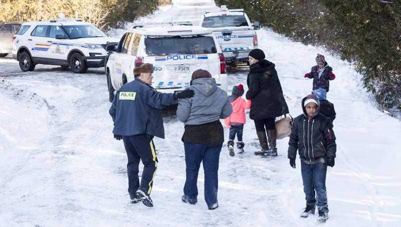 Family members from Somalia are escorted to waiting vehicles by RCMP officers following their crossing into Canada over the U.S.-Canada border