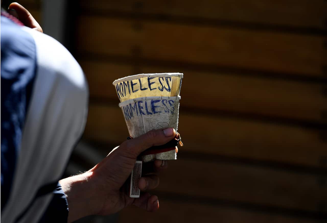 A homeless man holds a cup as he begs in Melbourne.