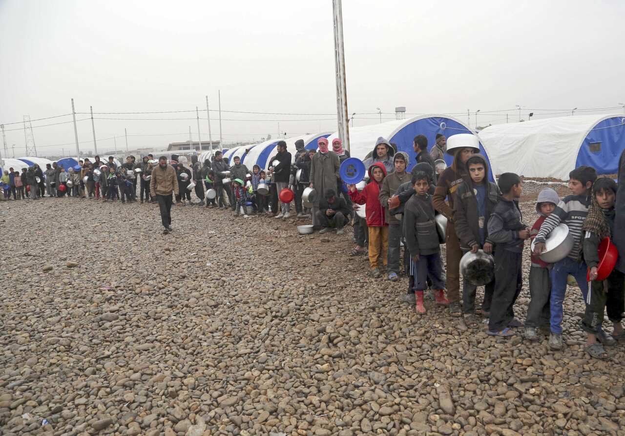 Displaced Iraqis line up to receive food at a camp for internally displaced people in Hamam al-Alil, some 10 kilometers south of Mosul, Iraq.