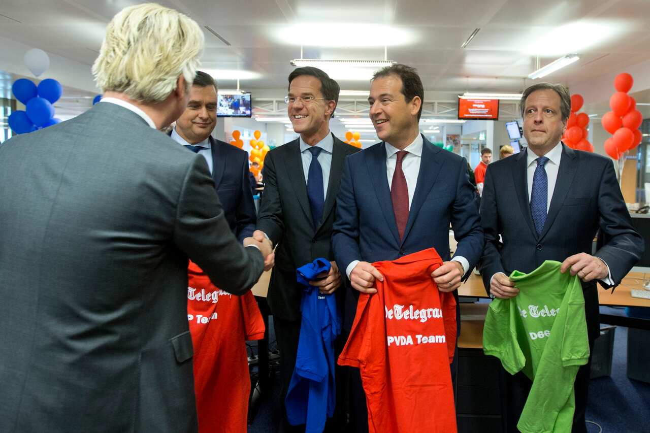 Wilders shakes hands with Rutte at a newspaper forum, leaders from the Socialist Party, D66 and the Labour party look on.