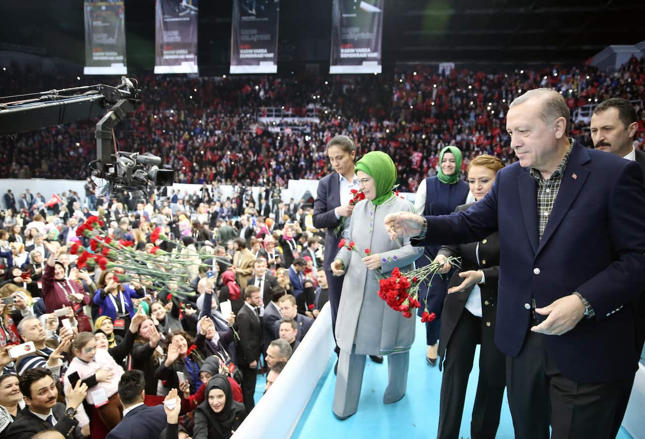 Turkish President Recep Tayyip Erdogan and his wife Emine Erdogan throw flowers to female supporters during the 'Woman and Democracy' meeting in Istanbul.