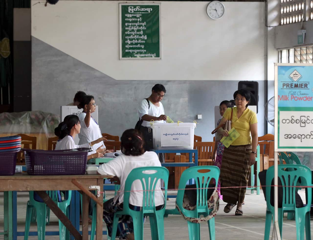 Officials of the Union Election Commission sit while people cast votes at a polling station in Yangon, Myanmar.