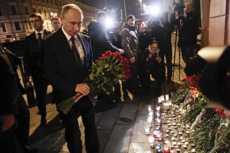 Russian President Vladimir Putin, left, lays flowers at a place near the Tekhnologichesky Institut subway station in St.Petersburg, Russia