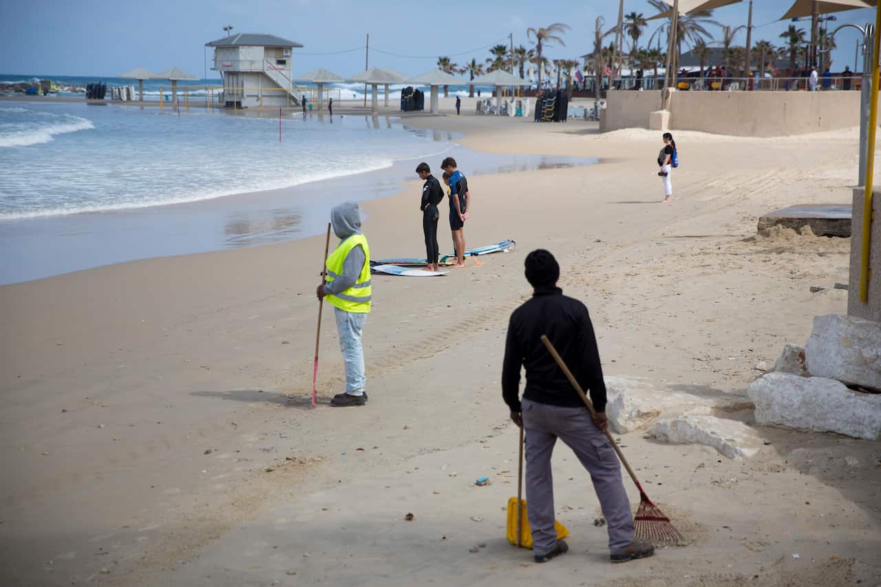 People stand still on the Mediterranean Sea beachfront in Netanya, Israel.