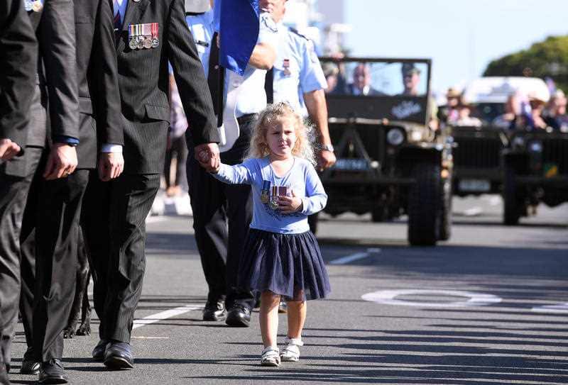 A young girl is seen wearing medals during an Anzac Day march in Southport on the Gold Coast