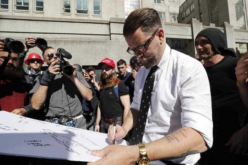 Vice Media co-founder Gavin McInnes (R) signs an autograph while being escorted to his car.