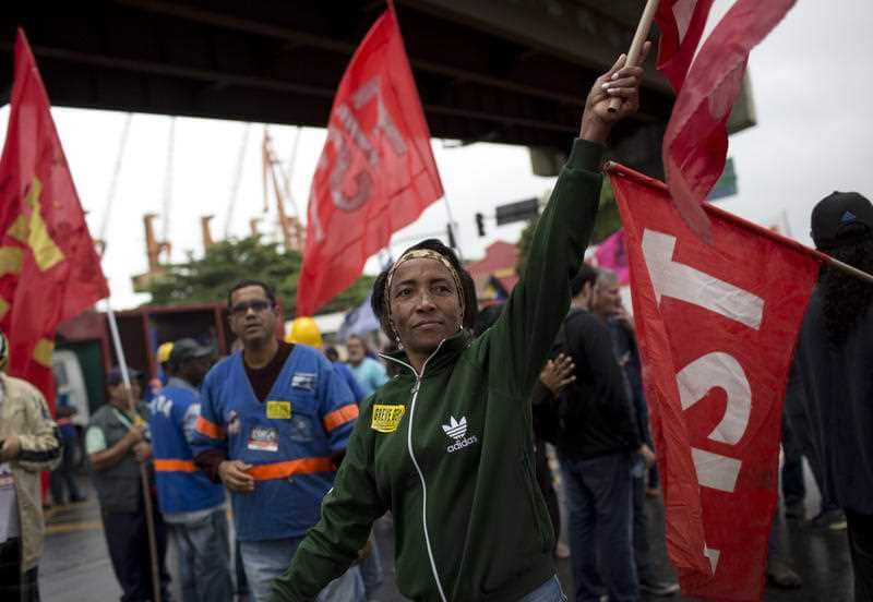 Demonstrators wave labor union banners during a protest at a bus station in Rio de Janeiro, Brazil