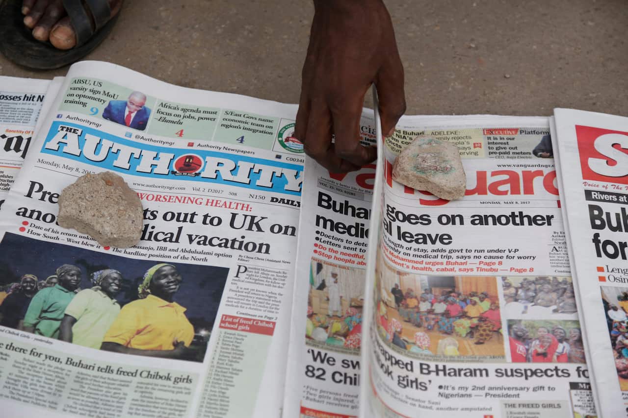 People read newspaper headlines, including stories of the released Nigerian Chibok kidnapped girls in Abuja, Nigeria