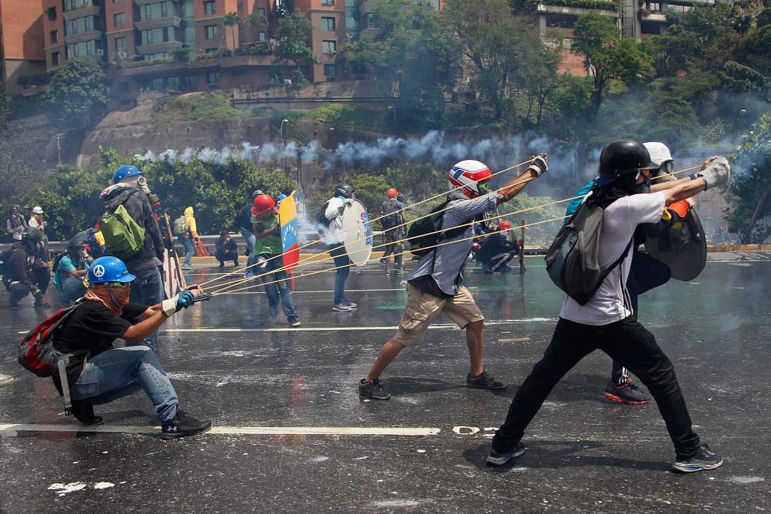Anti-government protesters aim a slingshot during clashes with security forces blocking a march to the Supreme Court in Caracas, May 10, 2017. 