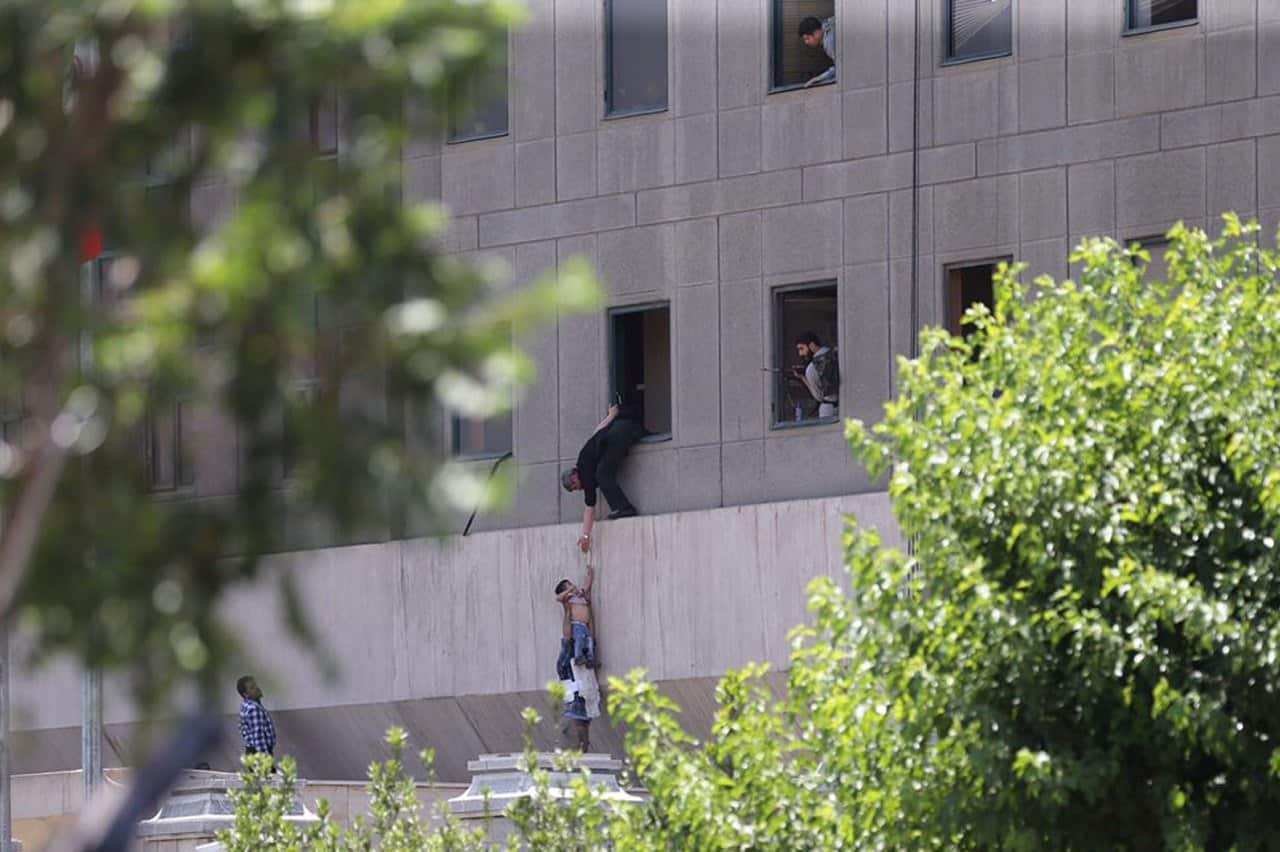 Iranian policemen try to help some civilians fleeing from the parliament building during an attack in Tehran, Iran