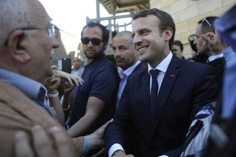 France's President Emmanuel Macron shakes hand with people