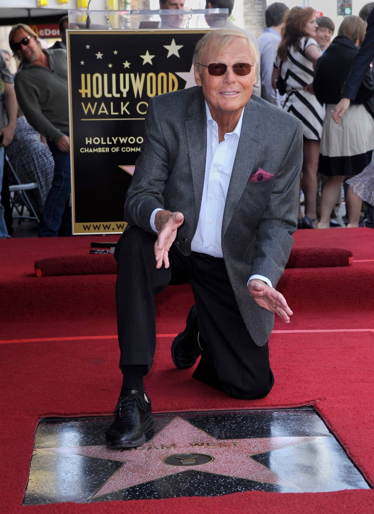 Adam West poses with his star on the Hollywood Walk of Fame during ceremony in 2012.