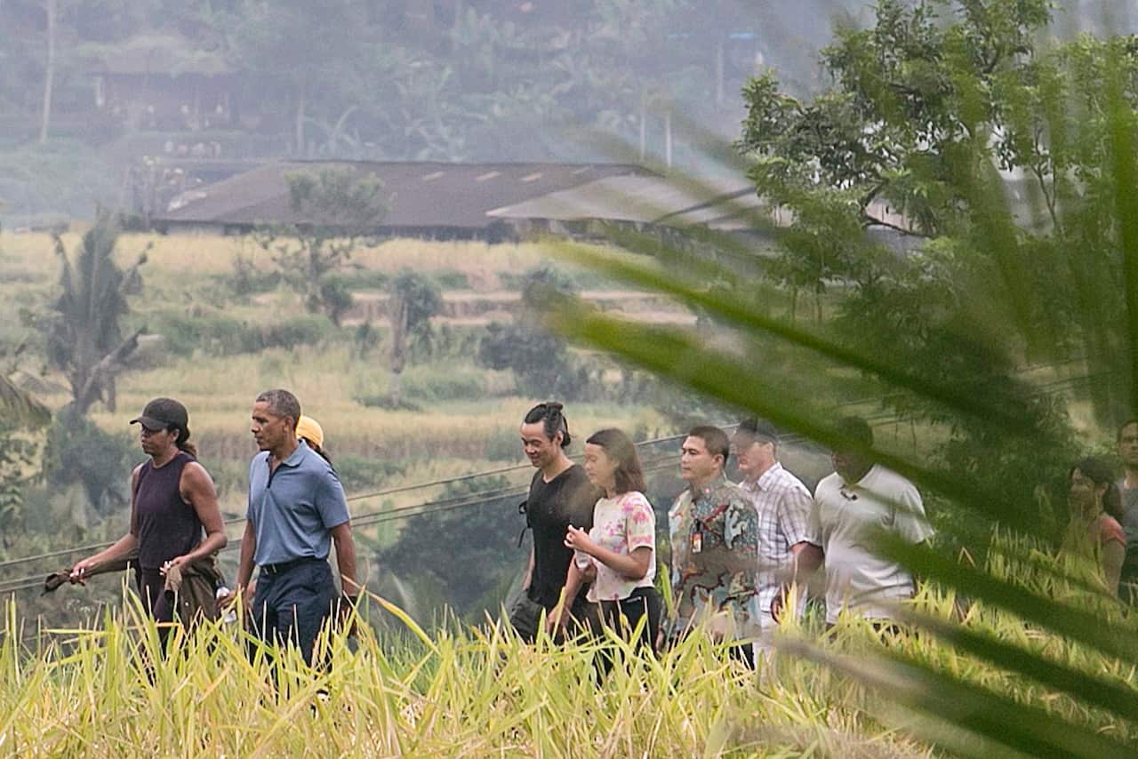 Former US president Barack Obama (2-L) and former first lady Michelle Obama (L) walk at Jatiluwih rice terrace.