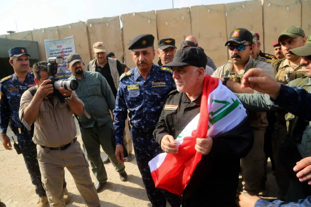 Iraq's Prime Minister Haider al-Abadi, center, holds a national flag upon his arrival in Mosul, Iraq.