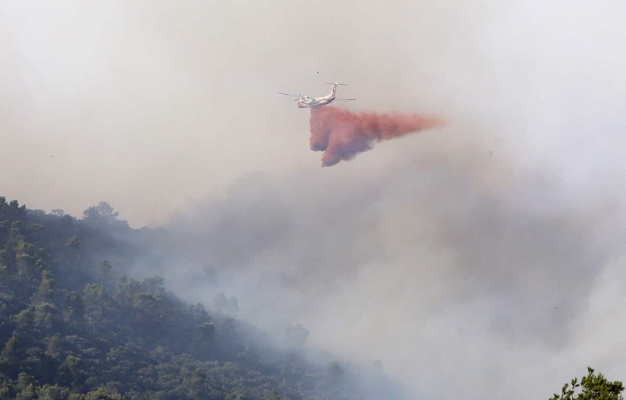 An anti-fire Dash airplane drops water over a forest fire near Seillons-Source- d'Argent, southern France, 