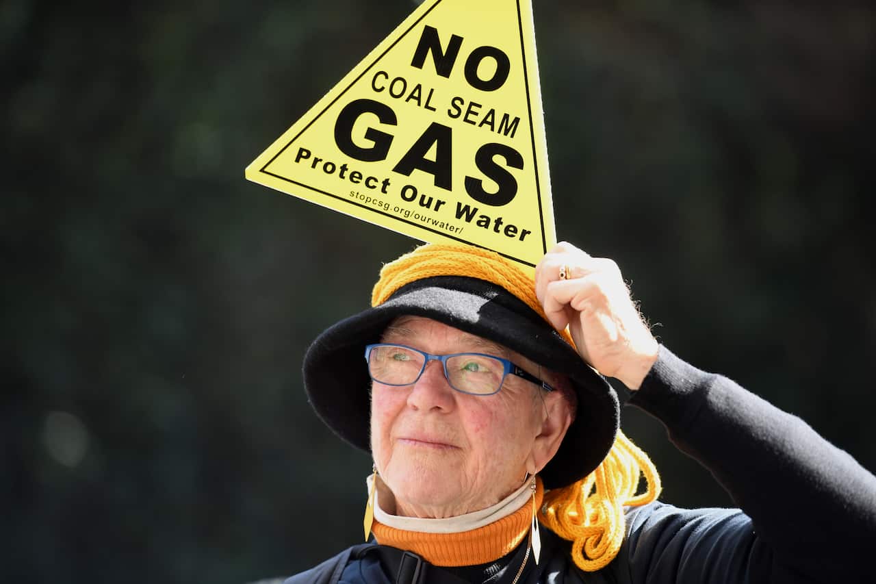 A demonstrator holds a placard to protest against Santos' plans for a major coal seam gas field near Narrabri, in the state's north west, in Sydney, Thursday, August 3, 2017. (AAP Image/Paul Miller) NO ARCHIVING