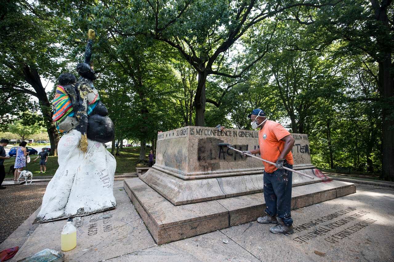 City workers remove graffiti from the base of what was once the Jackson-Lee Monument, a Confederate statue that city workers removed overnight in Baltimore.