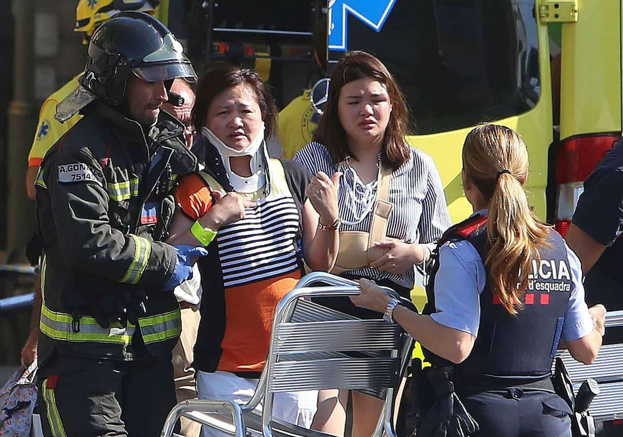 Injured people are treated in Barcelona, Spain, Thursday, Aug. 17, 2017 after a white van jumped the sidewalk in the historic Las Ramblas district