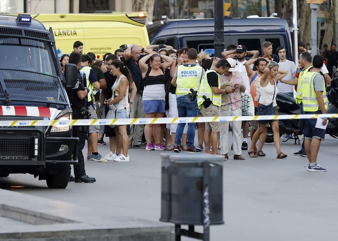 Mossos d'Esquadra Police officers set up a security perimeter and identify people near the site where a van crashes into pedestrians in Las Ramblas.