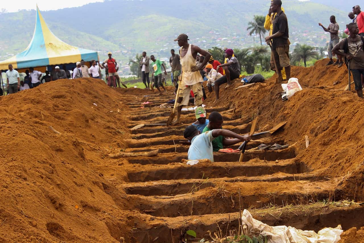 Workers dig mass graves for those who perished in a mudslide at a mass grave site in Waterloo, Sierra Leone