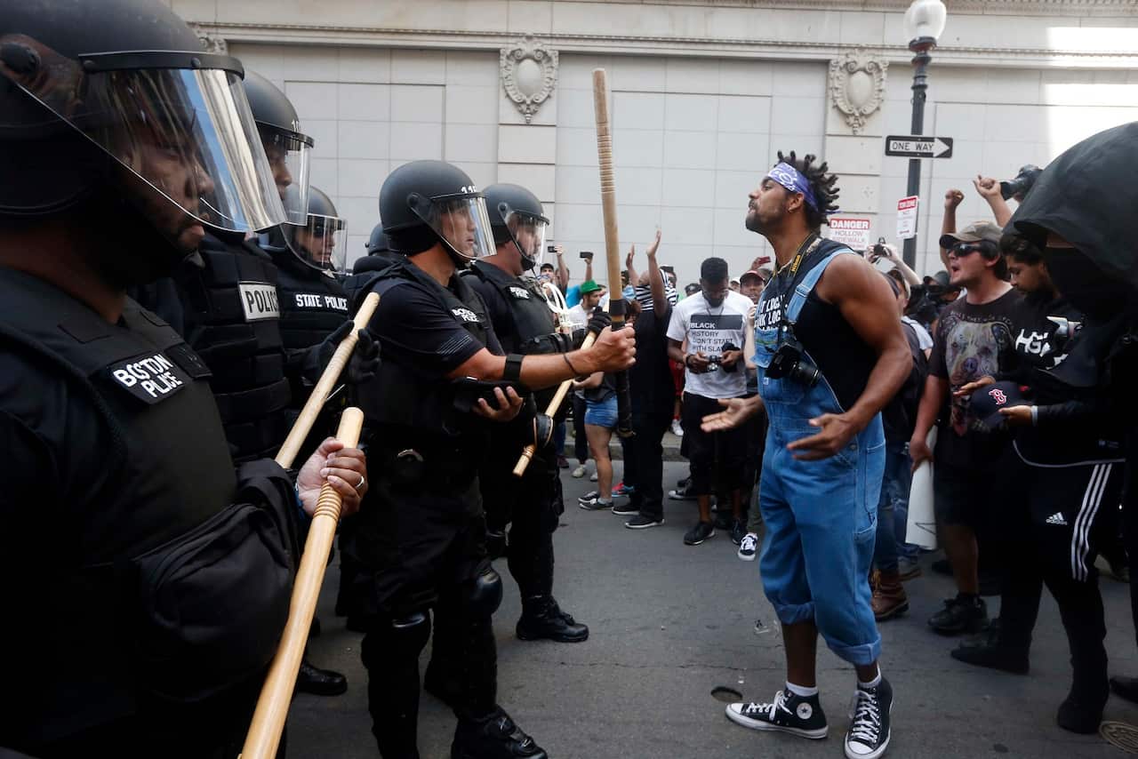 A counterprotester stands in front of police near a "Free Speech" rally staged by far-right activists
