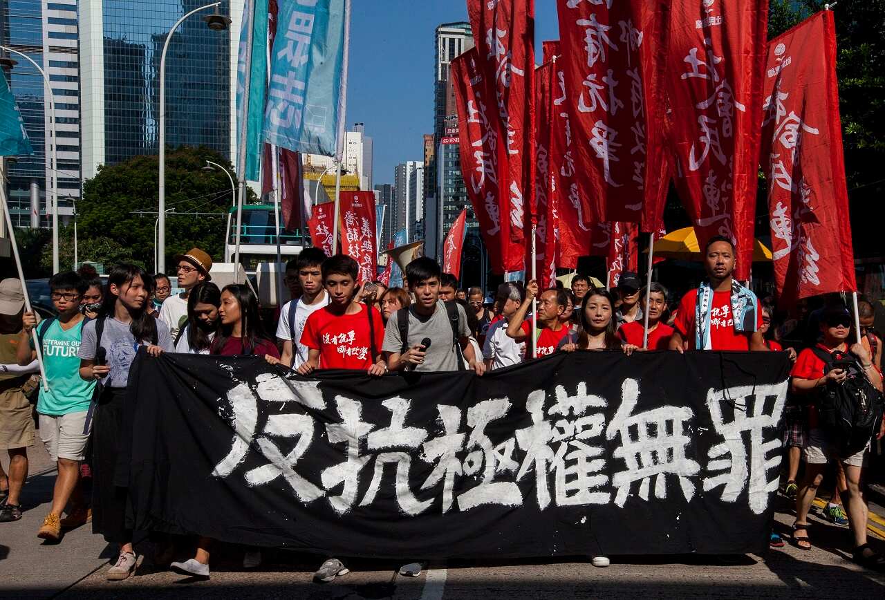 Students lead Hong Kong people with a Chinese banner that reads 'Protesting Authoritarianism is not a Crime' as they march through the streets in Hong Kong.