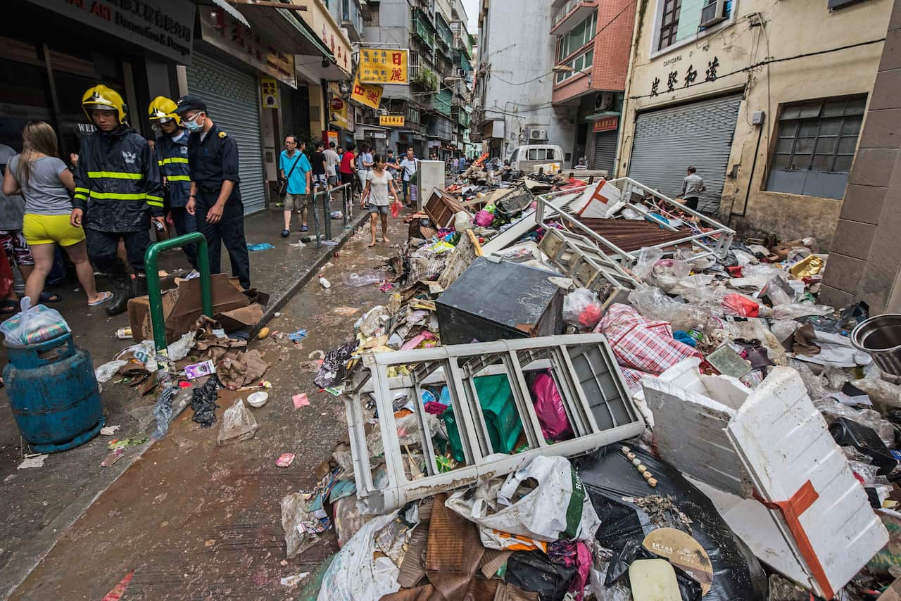 Firefighters and pedestrian pass by debris after the passage of Typhoon Hato in Macau