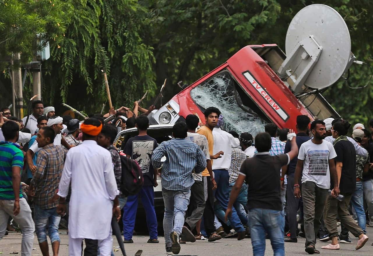 Dera Sacha Sauda sect supporters topple a vehicle near an Indian court in Panchkula, India, Friday, Aug. 25, 2017.