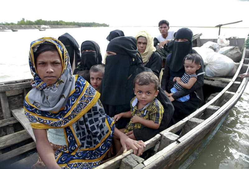 Members of Myanmar's Muslim Rohingya minority sit in a boat to cross a canal at Shah Porir Deep, in Teknak, Bangladesh, Thursday, Aug. 31, 2017. 