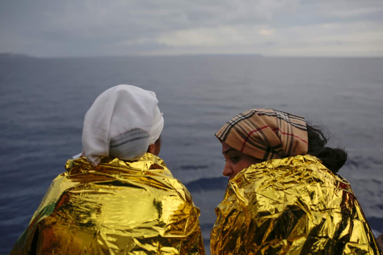 Two migrants look out on the Mediterranean Sea from the deck of a Spanish NGO vessel a day after being rescued off the Libyan coast on September 7, 2017.
