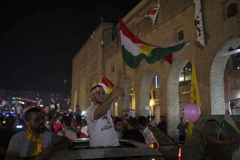 A man waves the Kurdish flag in the streets of Irbil after polling stations closed on Monday, Sept. 25, 2017. 
