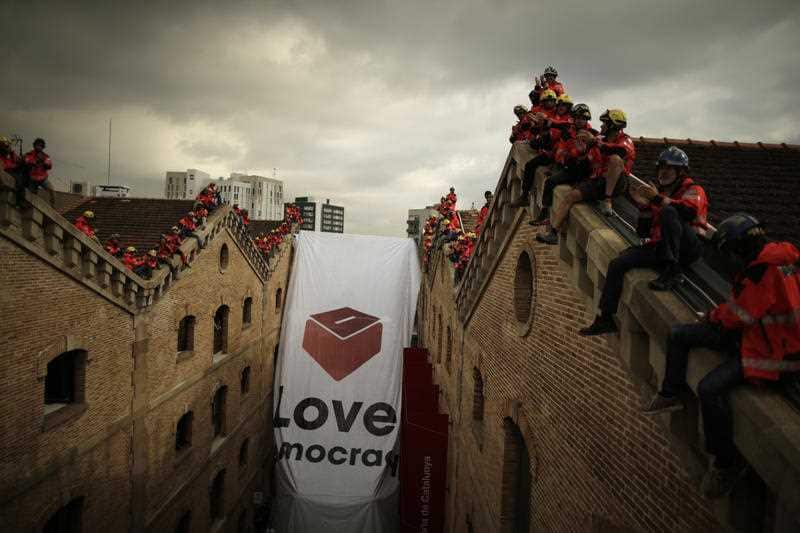 Catalan firefighters unfold a large banner with a ballot box at the Museum of History of Catalonia in Barcelona, Spain, Thursday, Sept. 28, 2017.