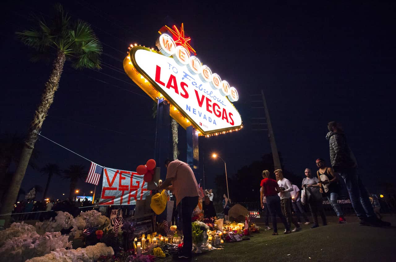 People pay tribute at the crosses installed behind the 'Welcome to Fabulous Las Vegas' sign in Las Vegas.