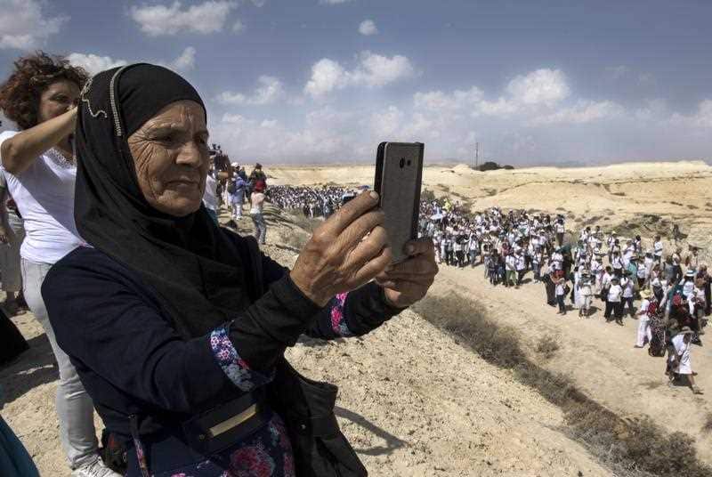 Palestinian and Israeli women take phone photographs of thousands of women taking part in a Peace march in the desert near Beit HaArava in the Jordan Valley