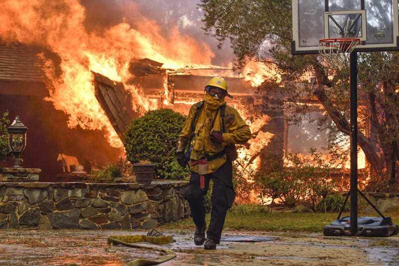 Firefighters work to extinguish a fire at a home as they battle a wildfire in Anaheim Hills, Calif., Monday, Oct. 9, 2017.