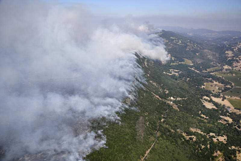Smoke rises as a wildfire burns in the hills east of Napa, Calif., Monday, Oct. 9, 2017.