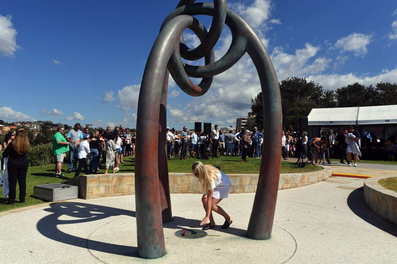 Bali Bombings survivor Ashleigh Airlie places a flower during a service at the Bali Memorial at Dolphins Point, Sydney, 11 October, 2017.