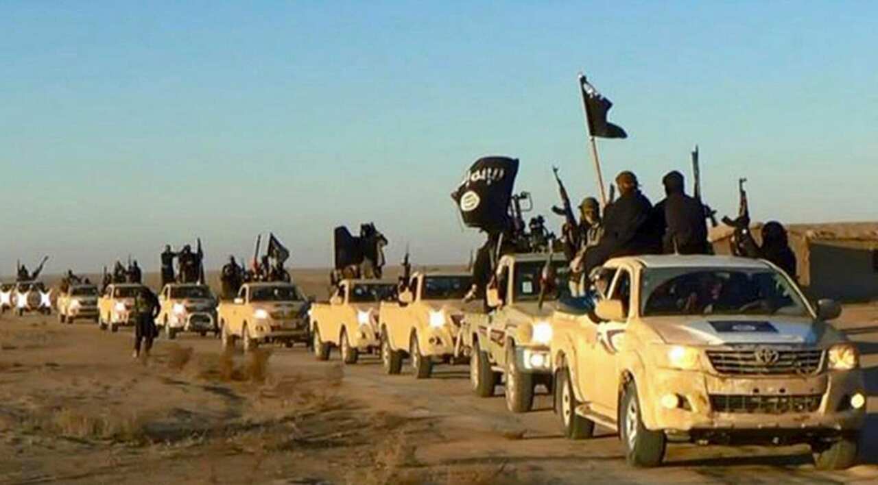 File photo of militants of the Islamic State group holding up their weapons and waving its flags on their vehicles in a convoy to Iraq, in Raqqa, Syria.