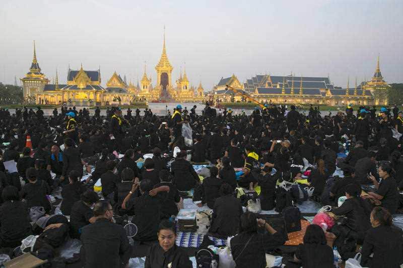 Thai mourners sits in front of the Royal Crematorium and funeral complex to take a part ceremony in Bangkok, Thailand, Thursday, Oct. 26, 2017.