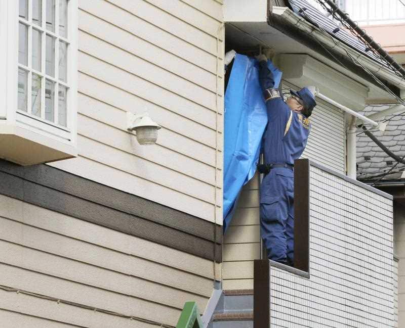 A police officer places a blue sheet on part of an apartment house in Zama, Kanagawa Prefecture on Oct. 31, 2017 where police found nine dismembered bodies in one of its units. The apartment is the home of 27-year-old Takahiro Shiraishi.