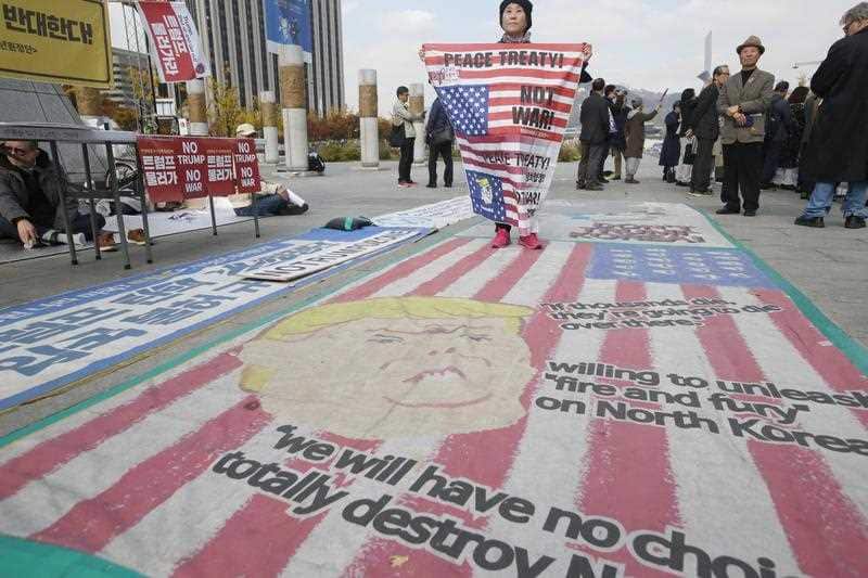 A South Korean protester stands on a cartoon depiction of US President Donald J. Trump during a rally held to show opposition to the US President's up coming visit.