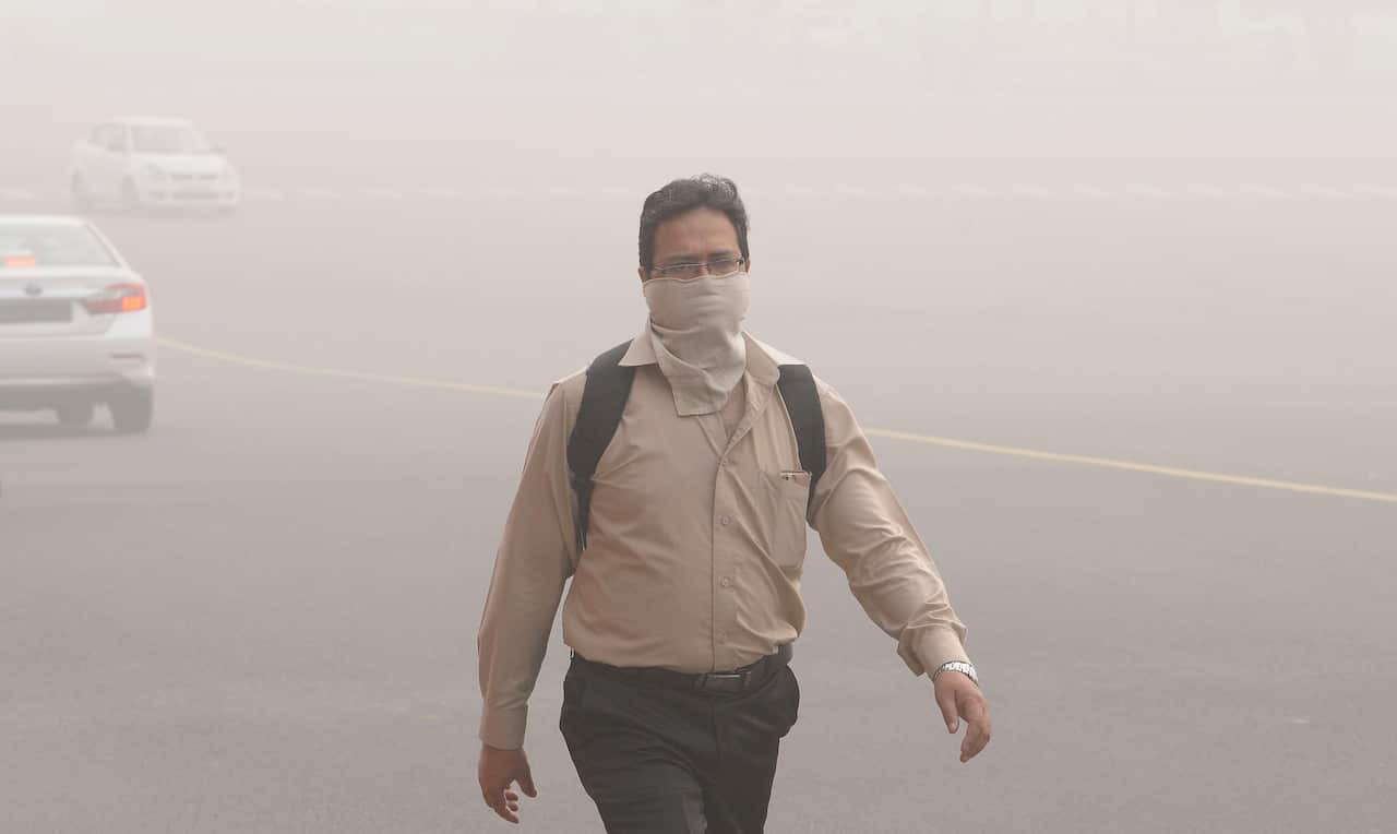 An Indian man with his face covered walks in New Delhi.