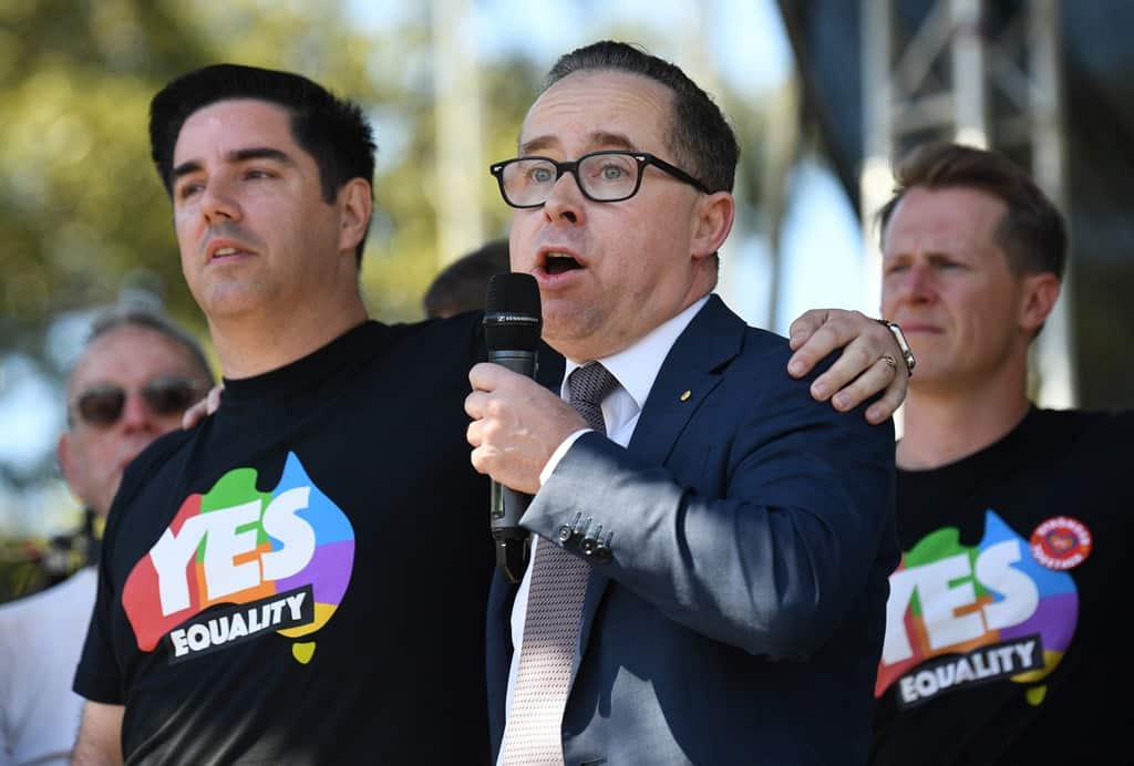 Alan Joyce, the CEO of Qantas, stands with his partner as he speaks after watching the same sex marriage vote result announcement